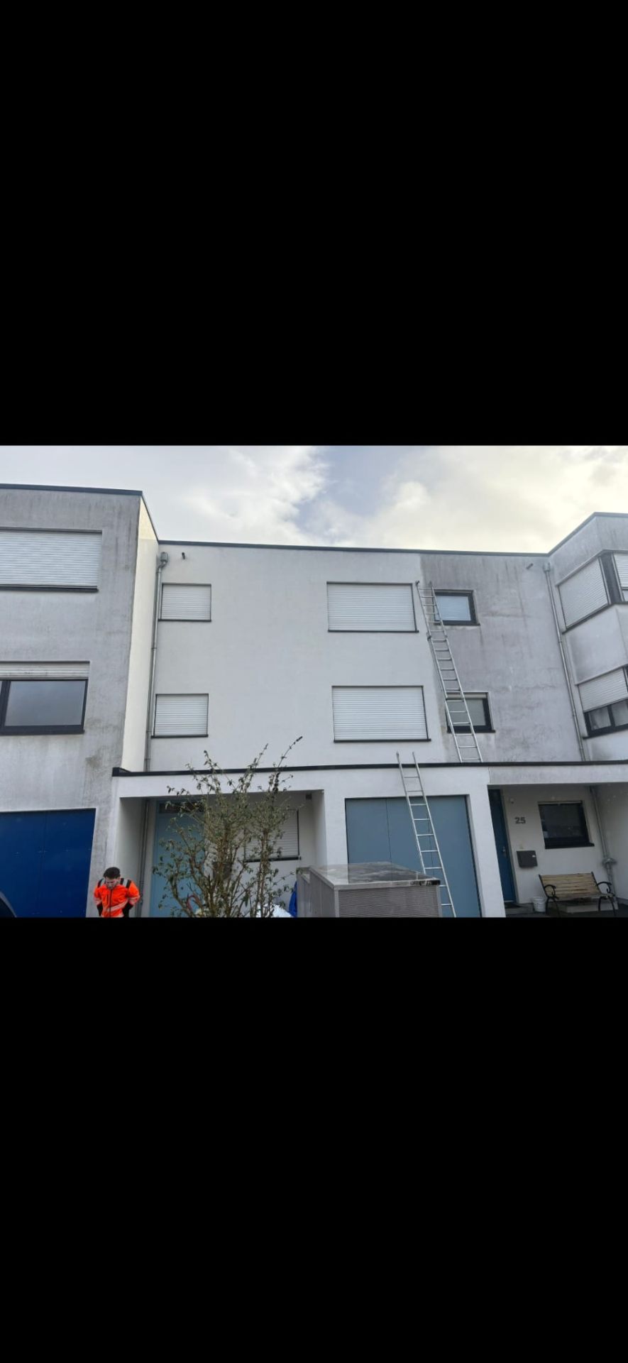 Render softwash in progress on a white townhouse facade